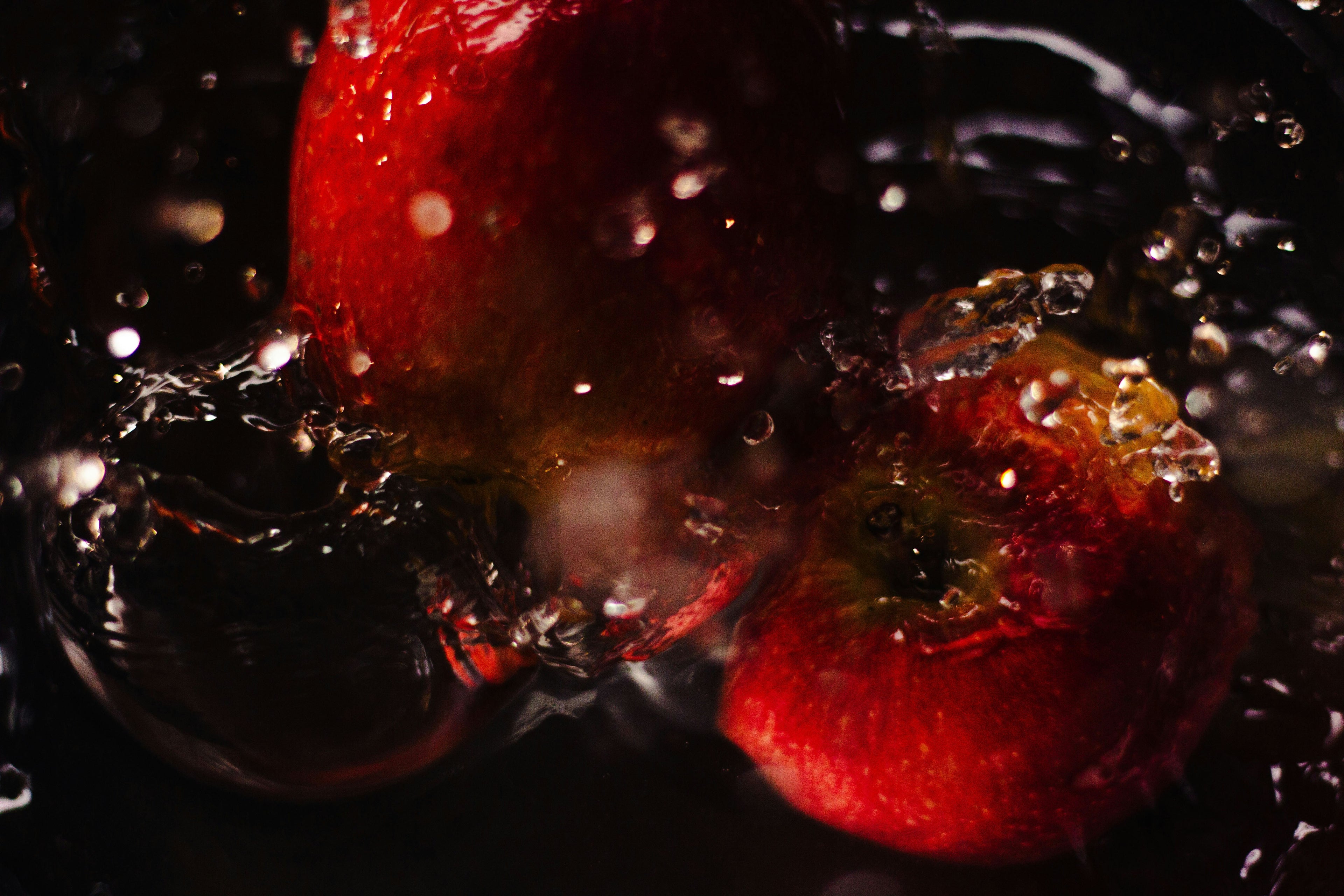 Apples splashing into water with a dark background