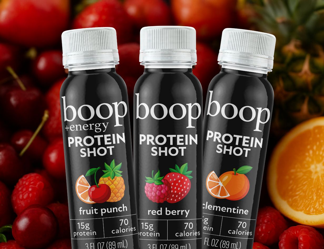 Three bottles of boop energy protein shot with fruit punch, red berry, and clementine flavors on a background of fruits.